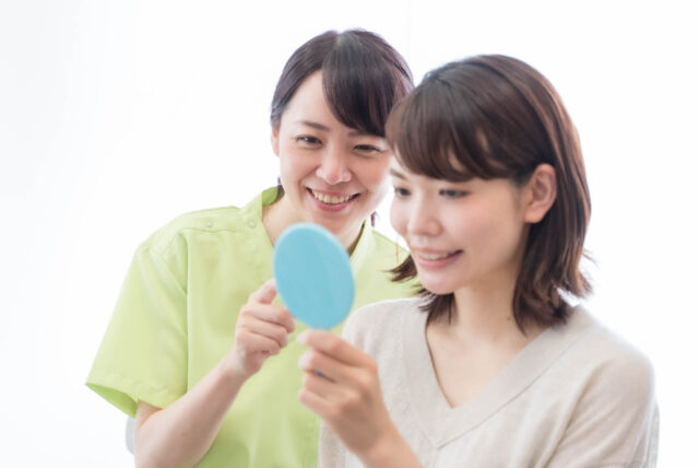 歯科衛生士と一緒に口元を鏡で確認する患者